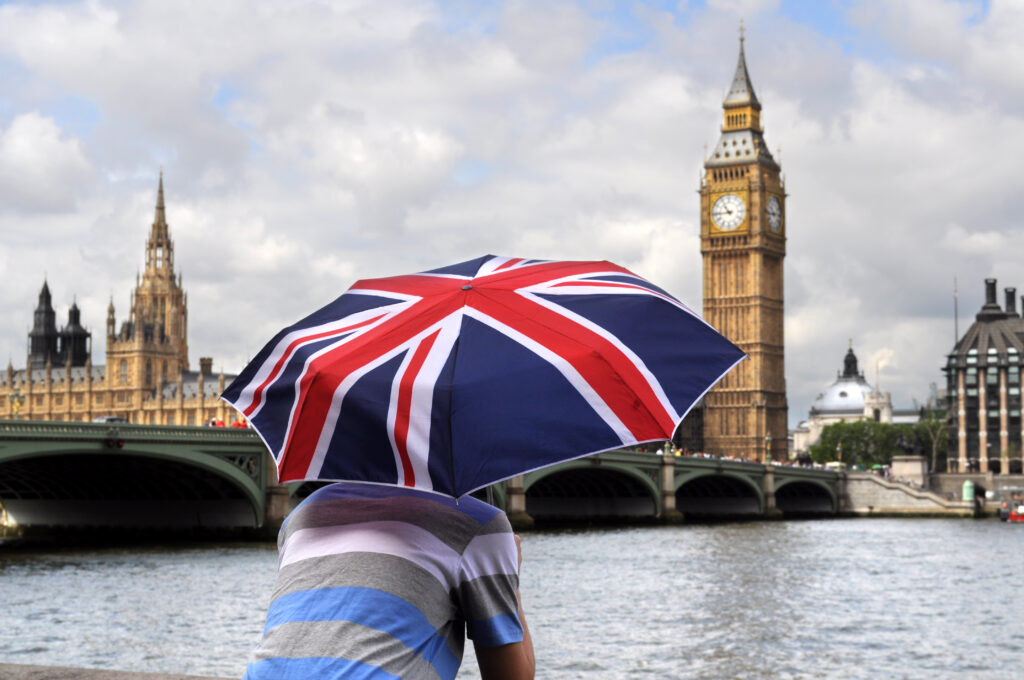 big ben and tourist with british flag umbrella in london